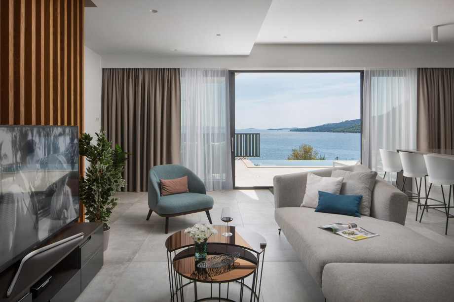 The elegantly furnished living room includes comfortable sofas, a TV, and air conditioning with a beautiful view of the sea