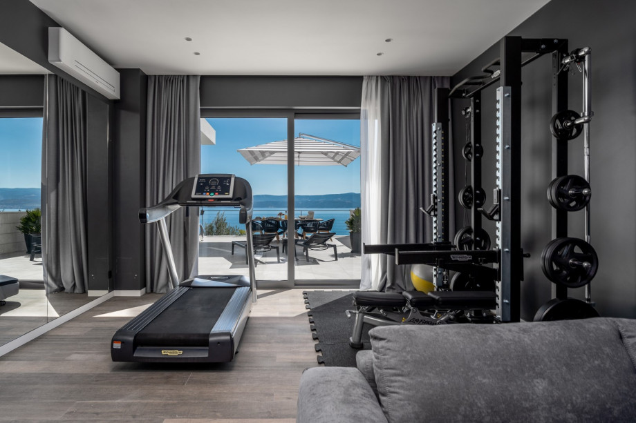 Gym with a Treadmill, Multi-Station Weight Bench, and Weights.