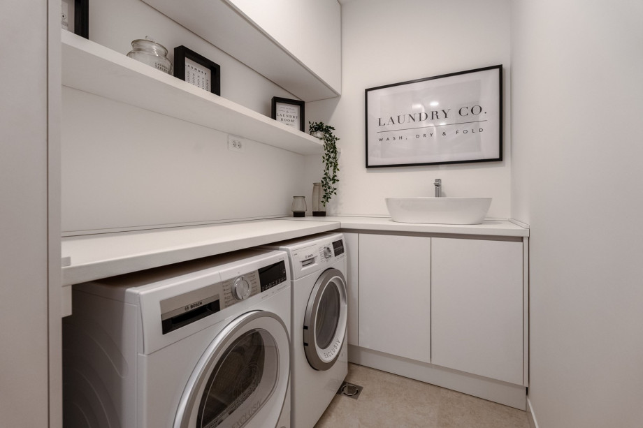 Nicely decorated Laundry with a washing machine, a dryer, and ironing amenities.