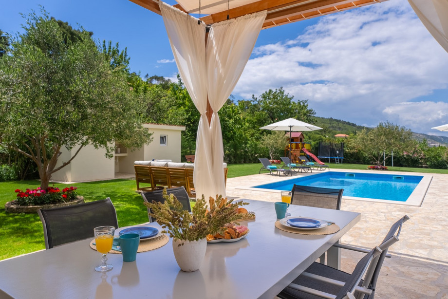 The outdoor dining area is covered and is located in front of the living room.