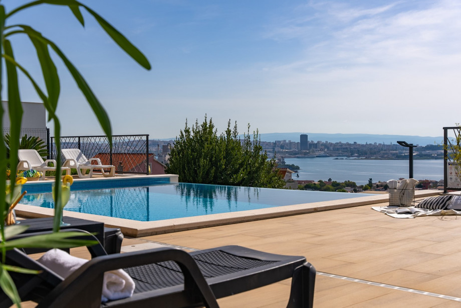 Spacious pool area with deck chairs and beautiful sea views