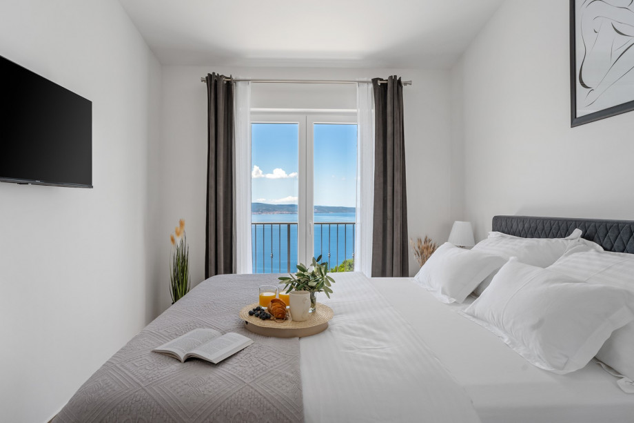 Bedroom No. 1 (12,6 square meters) on the first floor features a queen-size bed measuring 160 cm by 200 cm, an attached bathroom featuring a shower, a TV, air conditioning, sea views