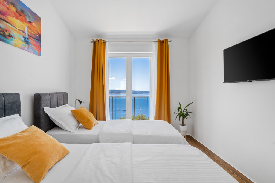 Third bedroom is 13 square meters and has two 90-by-200-cm single beds, a TV, air conditioning, a balcony, and views of the sea.