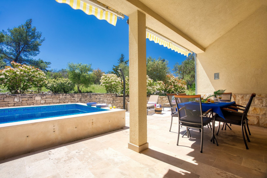There is a covered outdoor dining area and a traditional barbecue