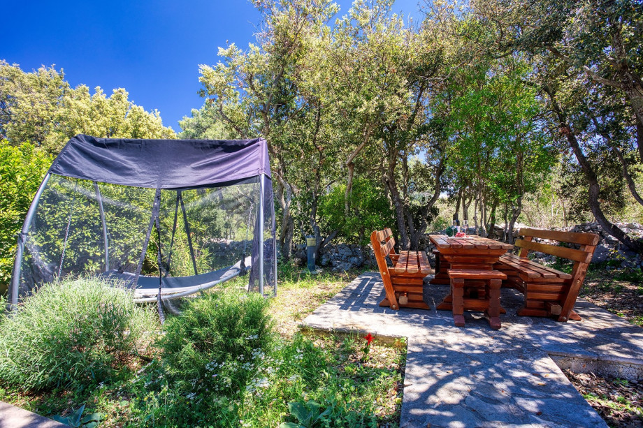 There is also a wooden table under the natural shade and next to there is a swing chair