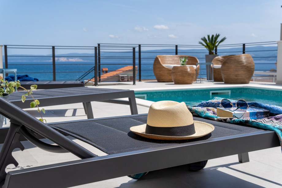 A sun deck area with 6 deck chairs, a comfy lounge corner