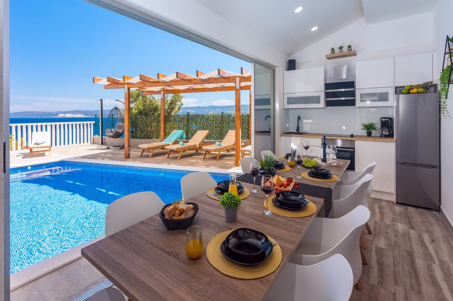 Dining area in summer kitchen connected with pool area and place for children