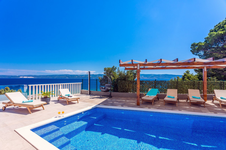 Pool area with 6 lounge chairs and outdoor furniture, open sea and island view