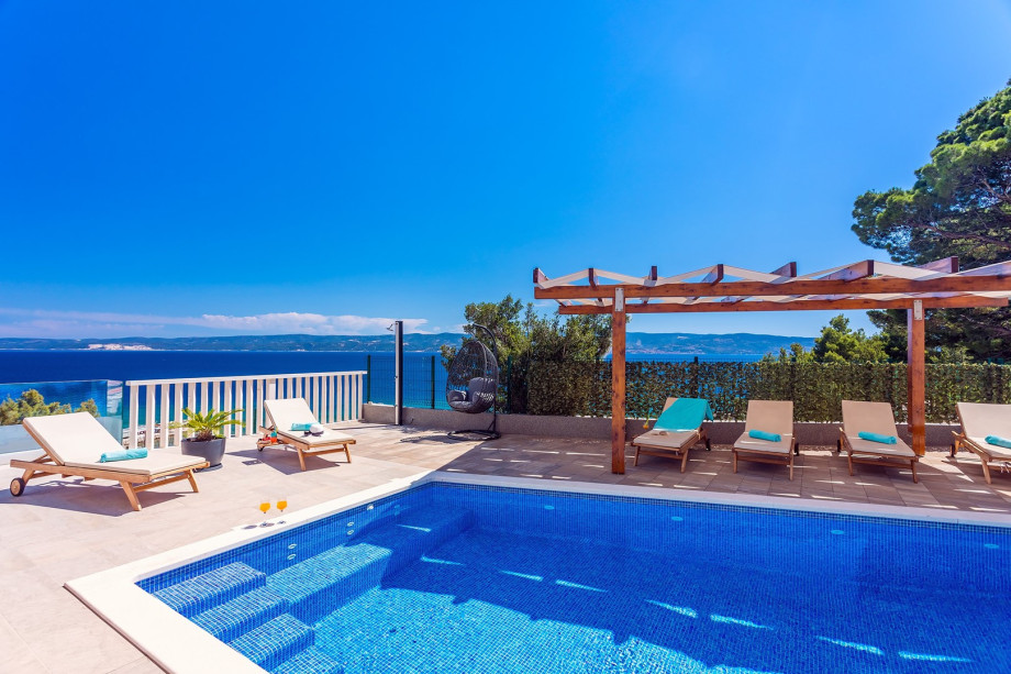 Pool area with 6 lounge chairs and outdoor furniture, open sea and island view