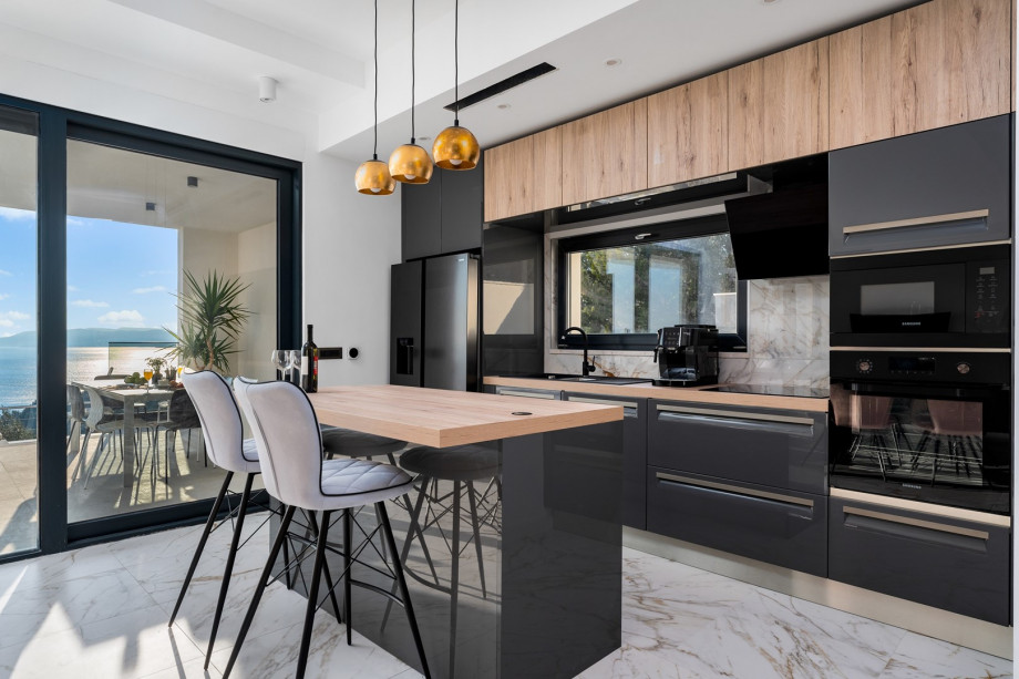 The living area is connected by an outdoor dining area and the pool area by glass floor-to-ceiling doors.