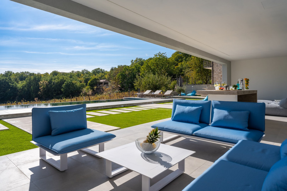 Covered area with a lounge area, a flat screen TV, a few lounge chairs with beanbags and a bar