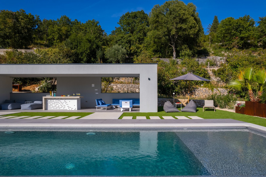 Covered area with a lounge area, a flat screen TV, a few lounge chairs with beanbags and a bar
