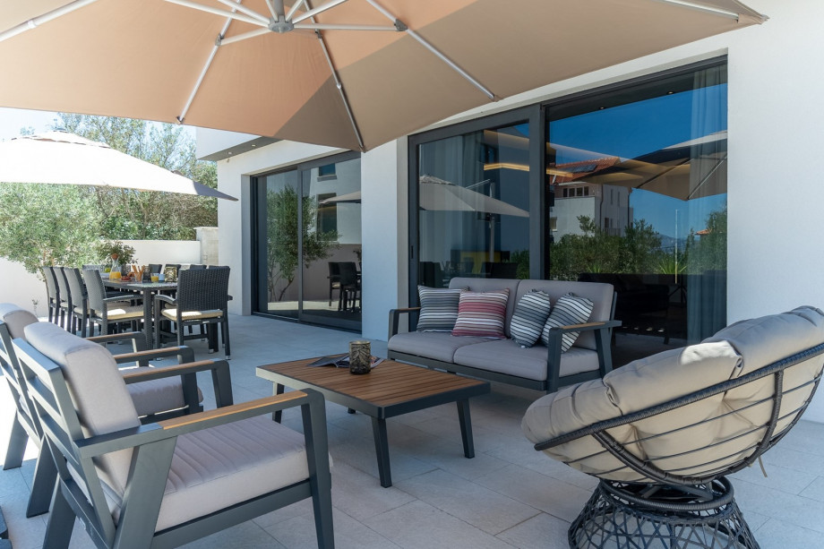 Outdoor dining area with the barbecue, a lounge corner, two sun umbrellas and nice sea views