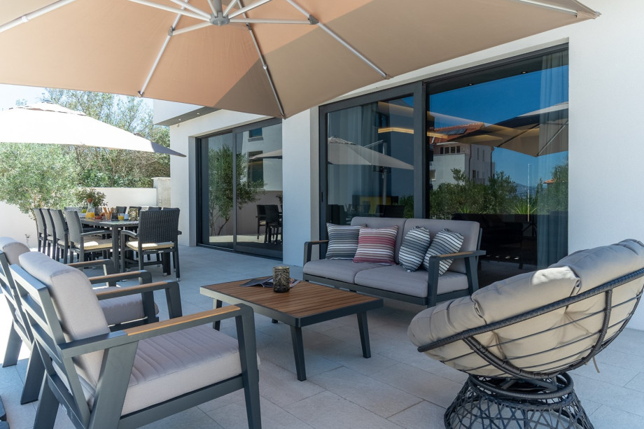 Outdoor dining area with the barbecue, a lounge corner, two sun umbrellas and nice sea views