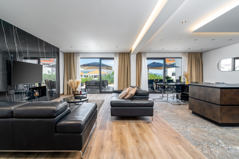 A spacious and very comfortable living room with flat screen TV, air-conditioning, glass doors toward the outdoor dining area