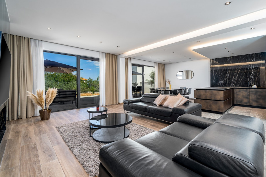 A spacious and very comfortable living room with flat screen TV, air-conditioning, glass doors toward the outdoor dining area