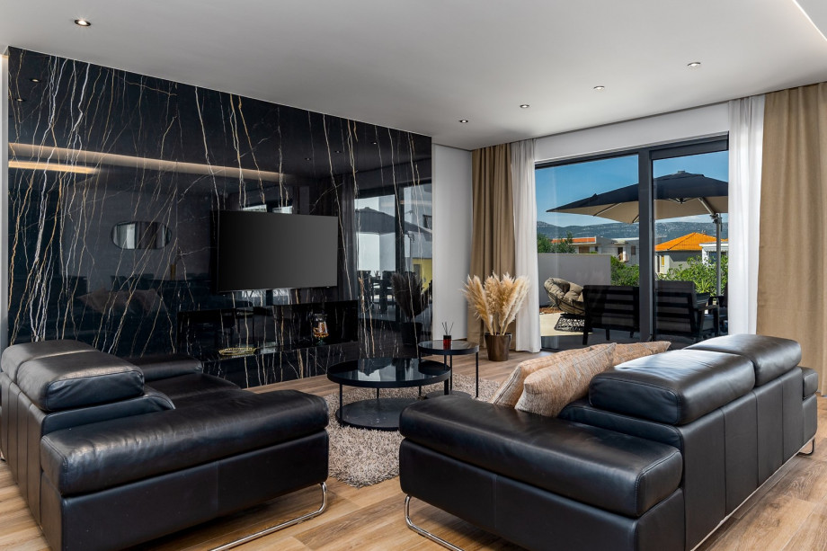 A spacious and very comfortable living room with flat screen TV, air-conditioning, glass doors toward the outdoor dining area