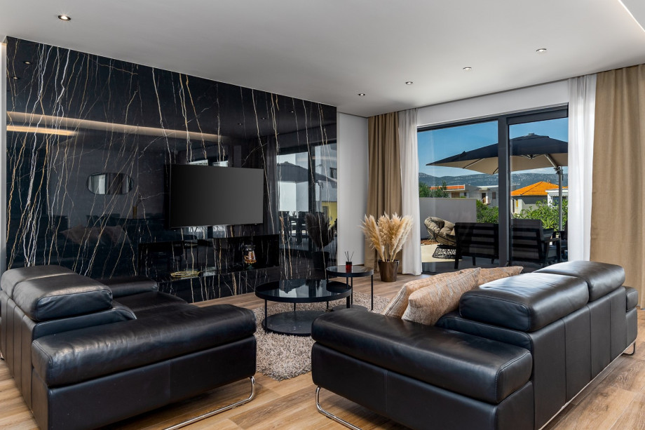 A spacious and very comfortable living room with flat screen TV, air-conditioning, glass doors toward the outdoor dining area