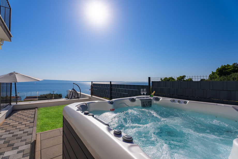 Ein Hot-Tub (ein Whirlpool) neben dem überdachten Essbereich im Freien (ein paar Stufen über dem Pool und der Sonnenterrasse)
