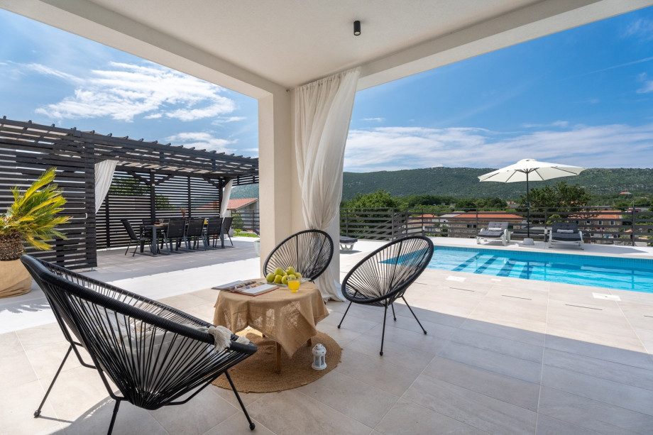 Der Sitzbereich im Freien befindet sich neben dem Pool und bietet einen atemberaubenden Blick auf die Berge.