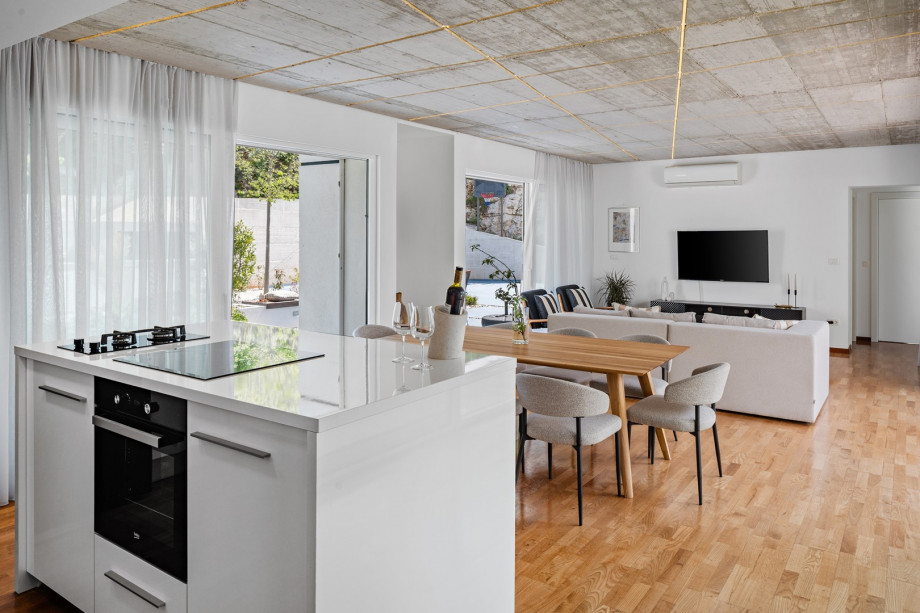 The fully equipped kitchen includes a kitchen island with a built-in sink, two ovens (gas and electric), a dishwasher, an ice maker, and a Dolce Gusto capsule coffee maker