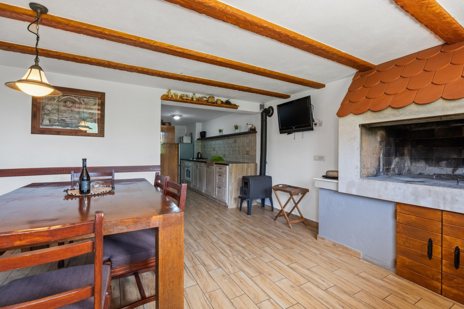 There is a summer kitchen with a traditional barbecue and dining area