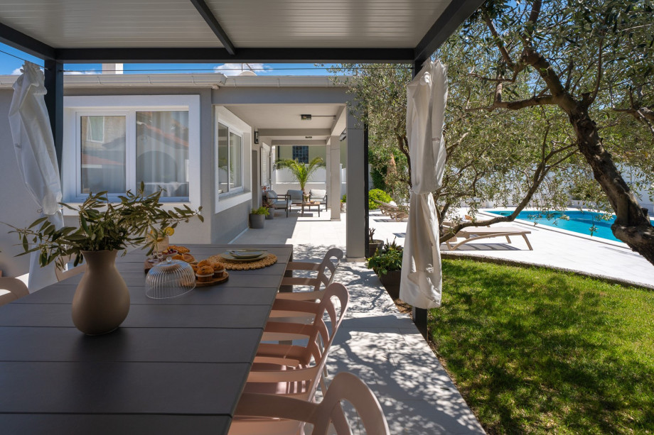Covered outdoor dining area surrounded by olive trees