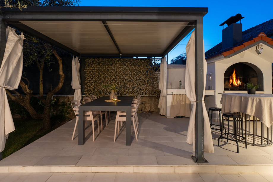 There is a covered outdoor dining area with a barbecue