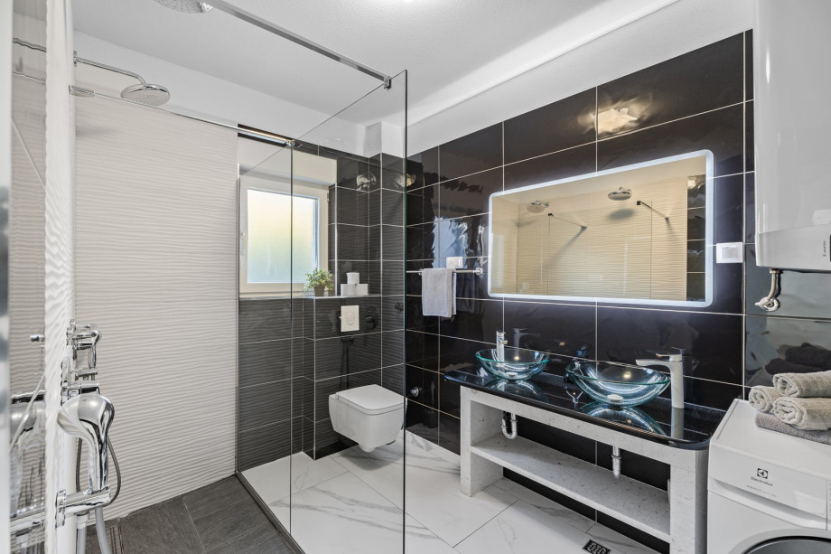 An elegantly decorated bathroom with a shower complete with a washing machine and dryer