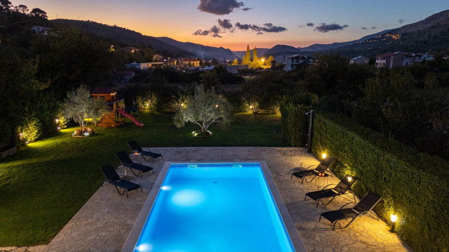 The villa offers stunning views of the valley and hills, adorned with Mediterranean plants.