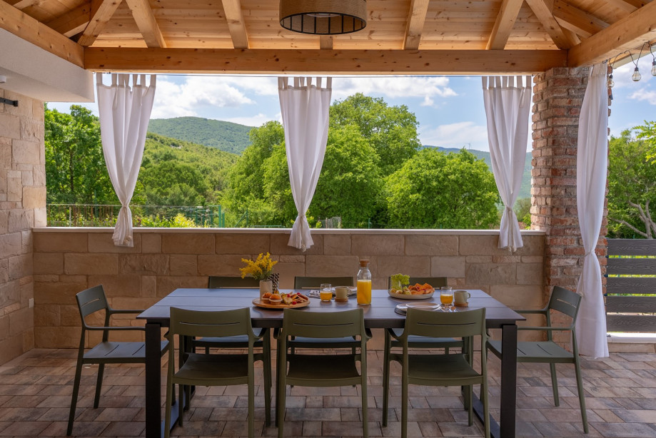 Covered outdoor dining area with a traditional wood/charcoal barbecue