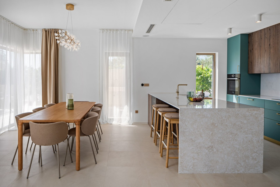 Esstisch, Kücheninsel mit Stolen und direkter Zugang zum überdachten Essbereich und ins Freie.