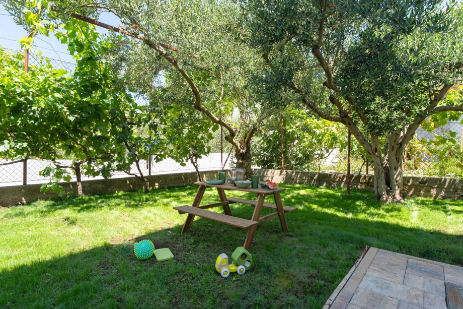 A grassy area with a kids' section with toys, a swing, and a sitting area for kids.