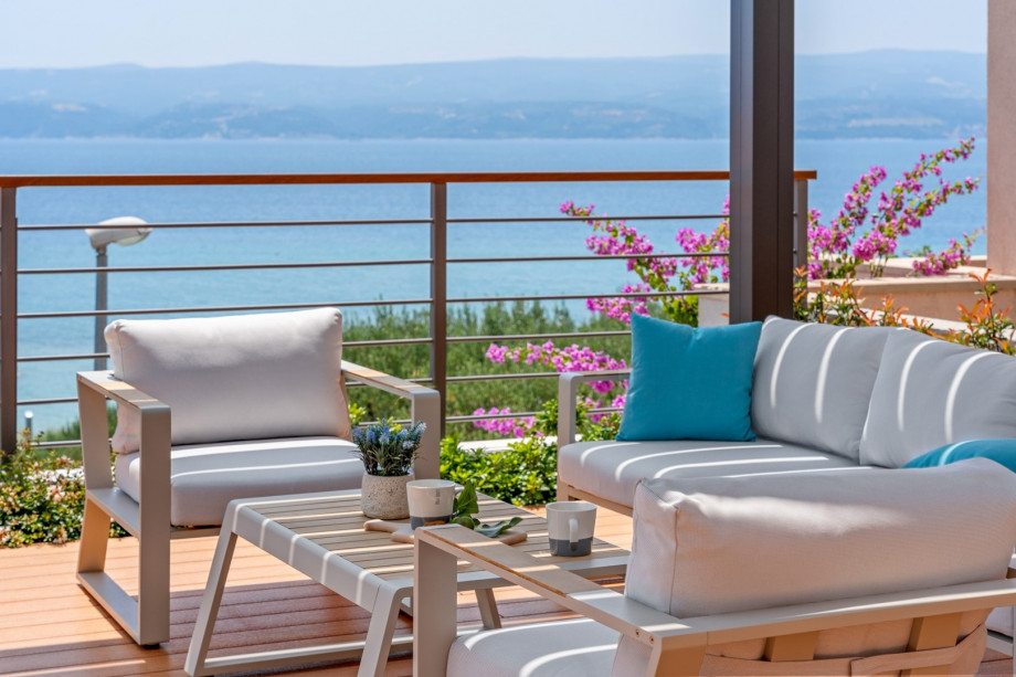 A sun-deck area with amazing sea views, a covered lounge corner, and an outdoor shower.