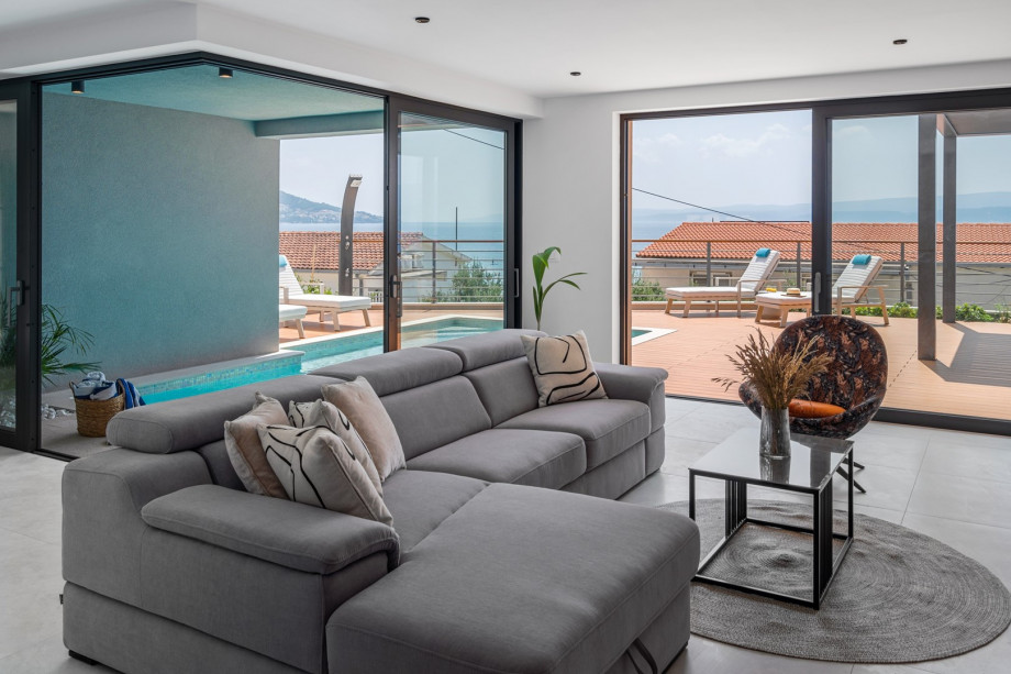 A spacious dining area, a living room with a flat-screen TV, and an overview of the sea and pool area.