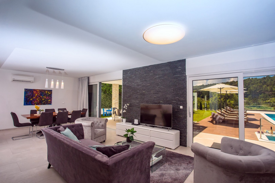 A living room with TV, and exit to a pool and outdoor dining area.