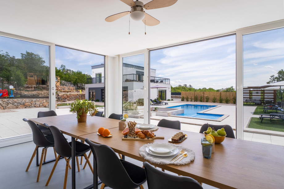 A summer kitchen with a dining table, dishwasher, TV, and darts
