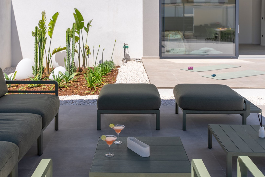 Relax in the outdoor sofa area with a refreshing drink, perfect for unwinding in the afternoon sun.