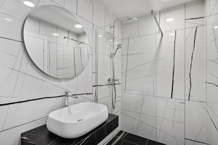 A bathroom with a shower and next to it is a laundry room with a washing machine and a dryer