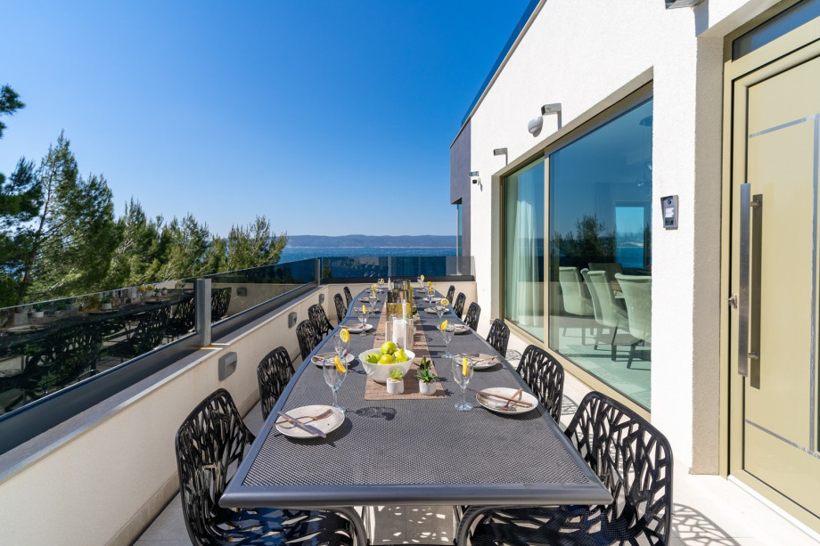 Large glass walls toward the outdoor dining area for 12 people with a gas barbecue
