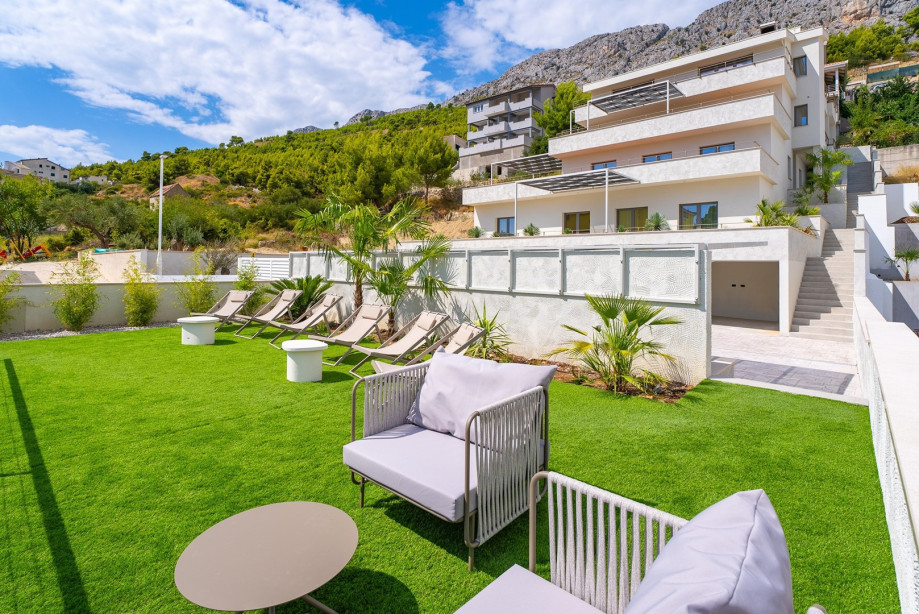Additional sun deck area is positioned a few steps up from the pool area, covered with an artificial grass plot offering a lounge corner, relaxing chairs, and sun umbrellas