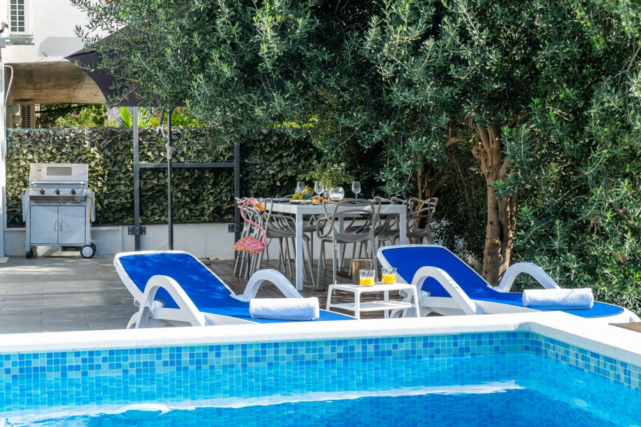 Outdoor dining area with a barbecue, surrounded with olive trees
