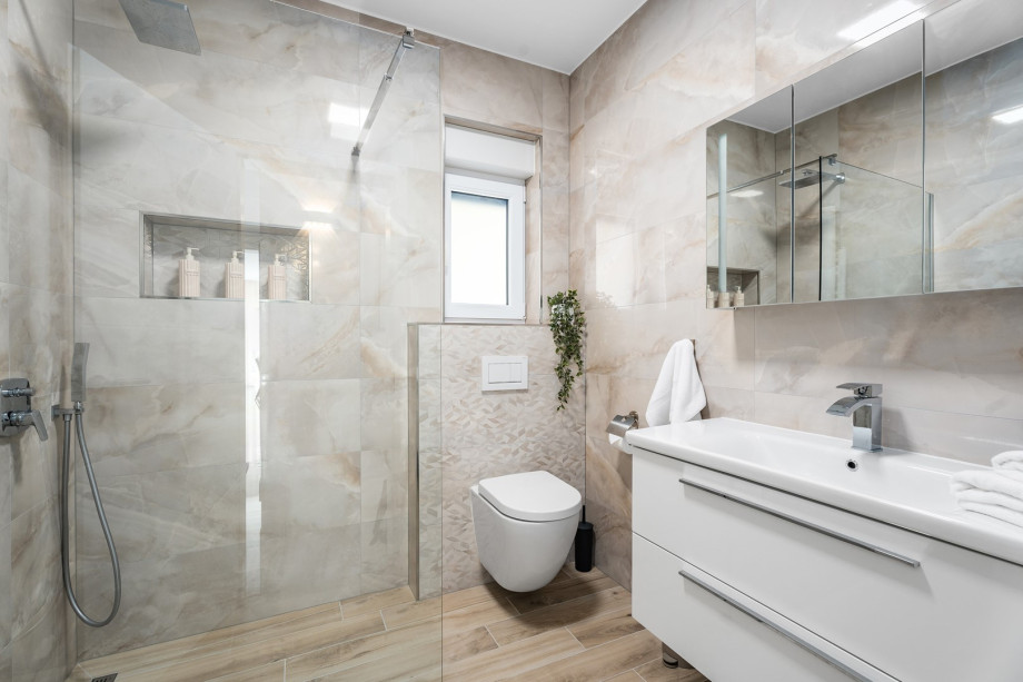 Ein stilvolles Familienbadezimmer mit Dusche, Toilette und Waschbecken.