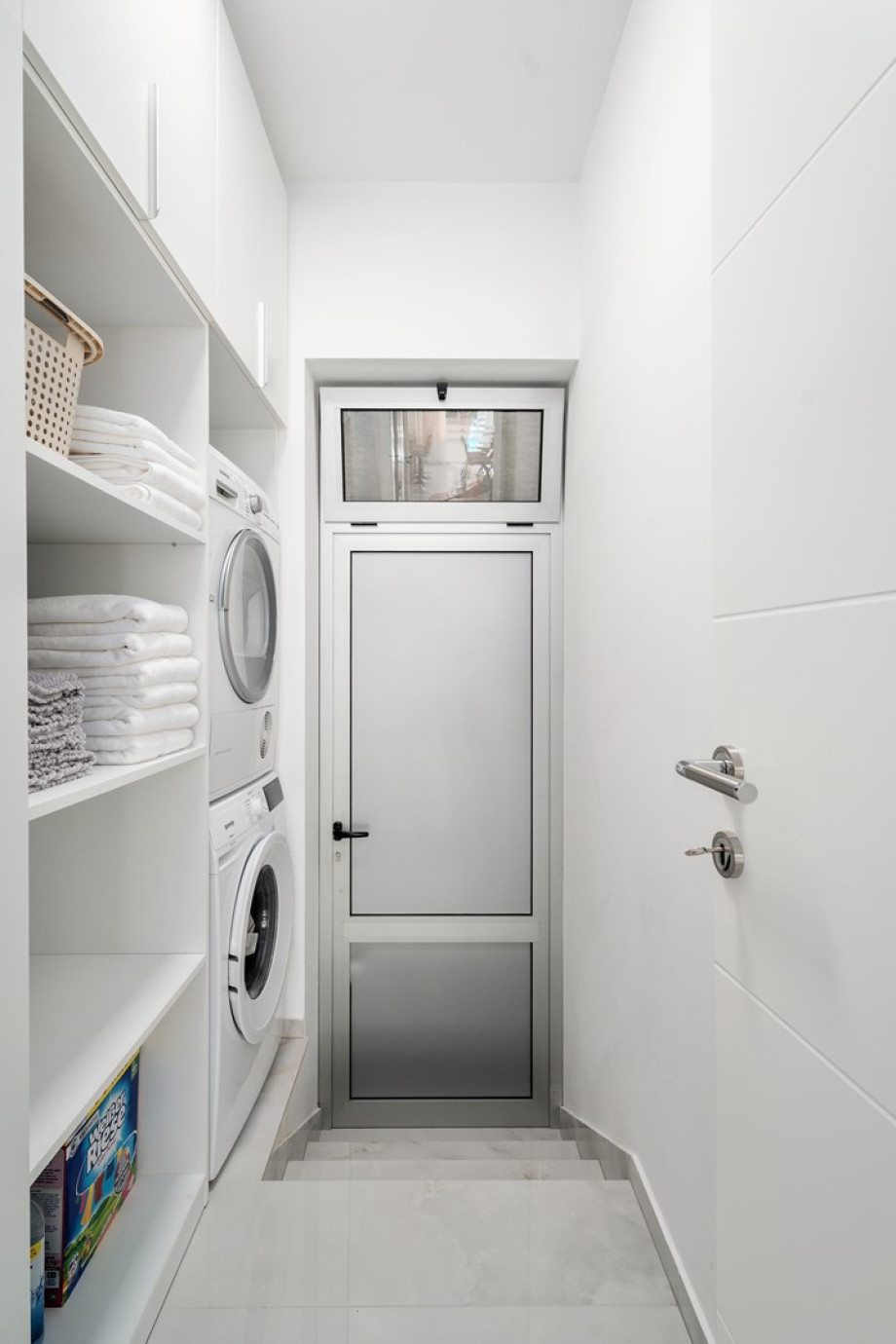 Ein Hauswirtschaftsraum mit Waschmaschine, Trockner und Bügelmöglichkeiten.
