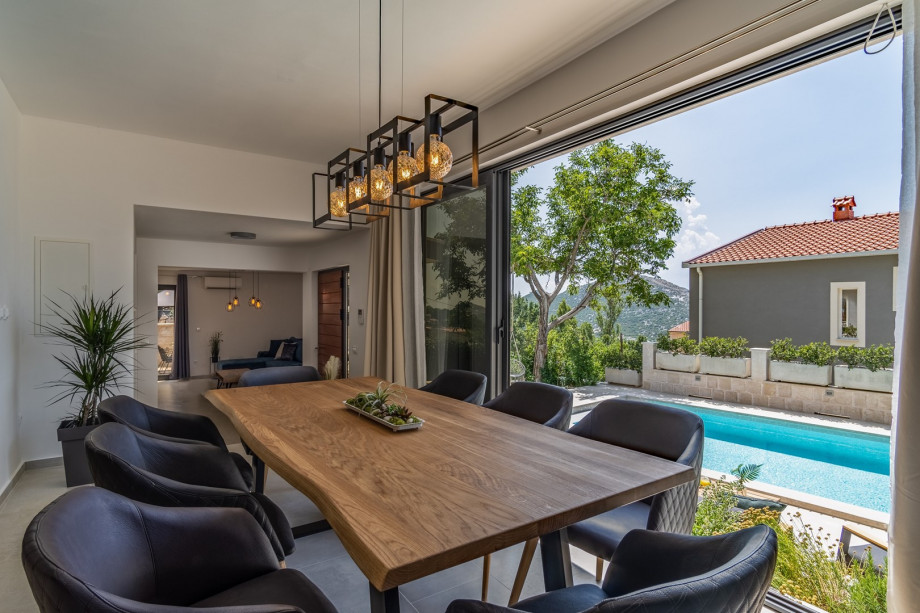 A dining area offers glass walls that can open so you can overview the pool area