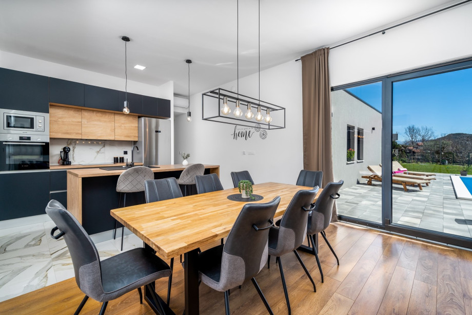 Stylish open plan kitchen and dinning area with sliding glass doors toward the pool area