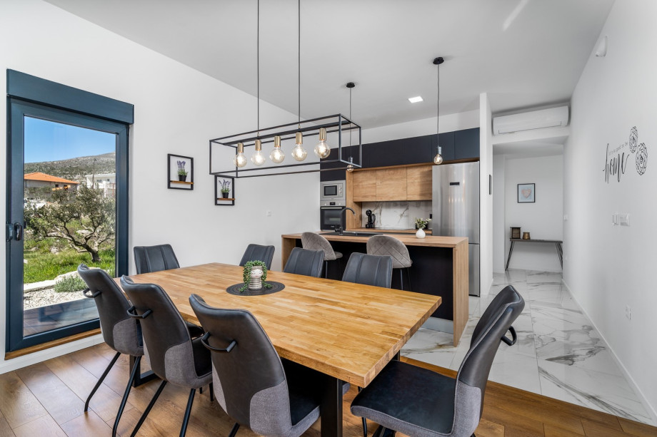 Stylish open plan kitchen and dinning area with sliding glass doors toward the pool area