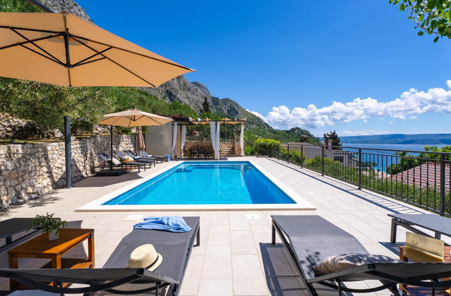 Pool area surrounded by nature, offering stunning mountain and a sea view.