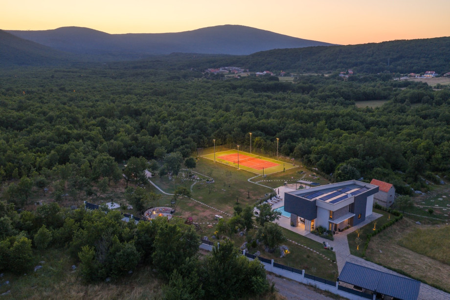An outdoor Tennis court with an artificial grass and tennis equipment and with the lighting for evening play