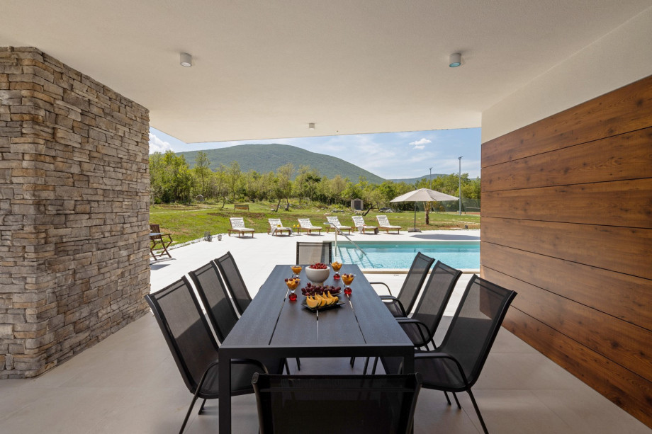 There is a covered outdoor dining area for 8 people with a gas barbecue